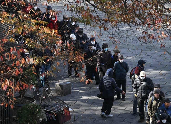 추운 날씨가 이어진 13일 서울 종로구 탑골공원 인근에서 노인들이 무료 급식을 받기 위해 줄지어 기다리고 있다. 2023.11.13 홍윤기 기자