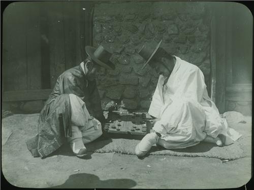 두 남성이 바닥에 앉아 장기를 두는 모습.