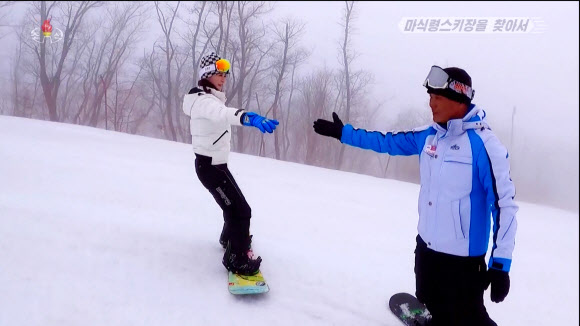 북한 조선중앙TV는 지난 3일 최근 마식령 스키장에서 판스키(스노보드)가 인기를 끌고 있다고 전했다. 현재 판스키 배우는 수가 대폭 늘어나 150~200명의 애호가들이 스키장에 등록돼 있다고 한다. 강일심 중앙TV 기자(왼쪽)가 강사의 지도를 받으며 스노보드를 타고 있다. 2024.3.4. 조선중앙TV 화면·연합뉴스
