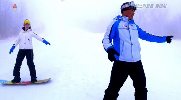 북한 조선중앙TV는 지난 3일 최근 마식령 스키장에서 판스키(스노보드)가 인기를 끌고 있다고 전했다. 현재 판스키 배우는 수가 대폭 늘어나 150~200명의 애호가들이 스키장에 등록돼 있다고 한다. 강일심 중앙TV 기자(왼쪽)가 강사의 지도를 받으며 스노보드를 타고 있다. 2024.3.4. 조선중앙TV 화면·연합뉴스