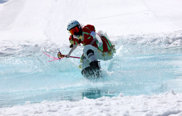 봄기운이 완연한 16일 강원 평창군 모나용평(용평스키장)에서 열린 물웅덩이 건너기 이색 이벤트인 ‘발왕수플래시’ 행사에서 이색 복장의 스키어와 스노보더가 물웅덩이를 건너고 있다. 2024.3.16 연합뉴스