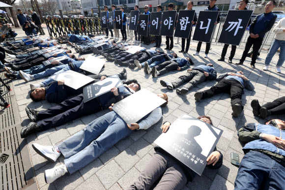 전국공무원노동조합과 대한민국공무원노동조합총연맹 관계자들이 18일 오전 서울 용산구 대통령실 앞에서 열린 ‘공무원 악성민원 대책 마련 촉구 기자회견’에서 ‘악성민원 희생자 추모 다잉 퍼포먼스’를 하고 있다. 2024.3.18 연합뉴스