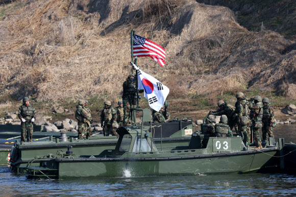 20일 경기도 연천군에서 실시된 한미연합 제병협동 도하훈련에서 육군 장병이 미군 장병과 부교를 완성한 후 태극기와 성조기를 걸고 있다.  이번 훈련에는 육군 5공병여단과 5기갑여단, 미2사단/한미연합사단 장병이 참가했다. 2024.3.20  연합뉴스