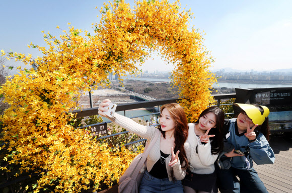 오후로 접어들면서 다소 포근해진 21일 개나리로 유명한 서울 성동구 응봉산을 찾은 시민들이 모형 개나리 포토존에서 기념 촬영을 하고 있다. 2024.3.21 연합뉴스