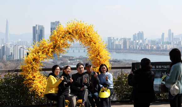 오후로 접어들면서 다소 포근해진 21일 개나리로 유명한 서울 성동구 응봉산을 찾은 시민들이 모형 개나리 포토존에서 기념촬영을 하고 있다. 2024.3.21 연합뉴스