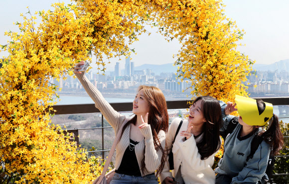 오후로 접어들면서 다소 포근해진 21일 개나리로 유명한 서울 성동구 응봉산을 찾은 시민들이 모형 개나리 포토존에서 기념촬영을 하고 있다. 2024.3.21 연합뉴스