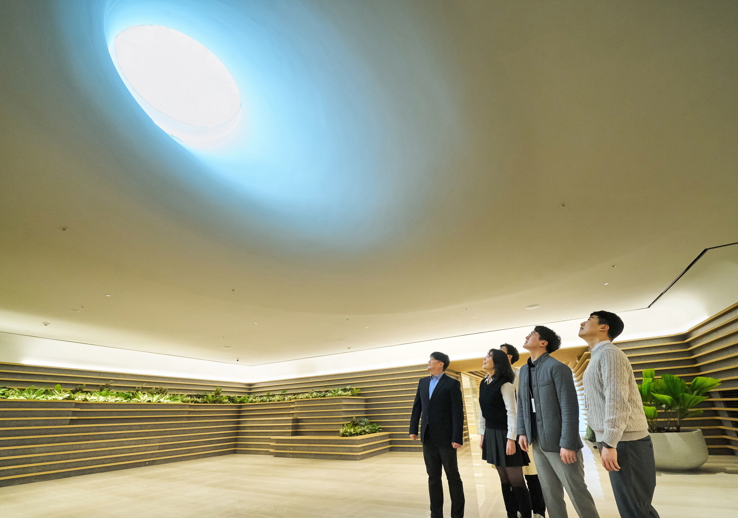 LG 직원들이 LG트윈타워 지하 1층에 새로 조성된 ‘틴들’에서 햇빛이 들어오는 천장을 바라보고 있다. ‘구름 사이로 빛이 쏟아지는 자연 현상’을 의미하는 ‘틴들’은 자연채광이 천장의 창을 통해 실내를 비춘다. ㈜LG 제공