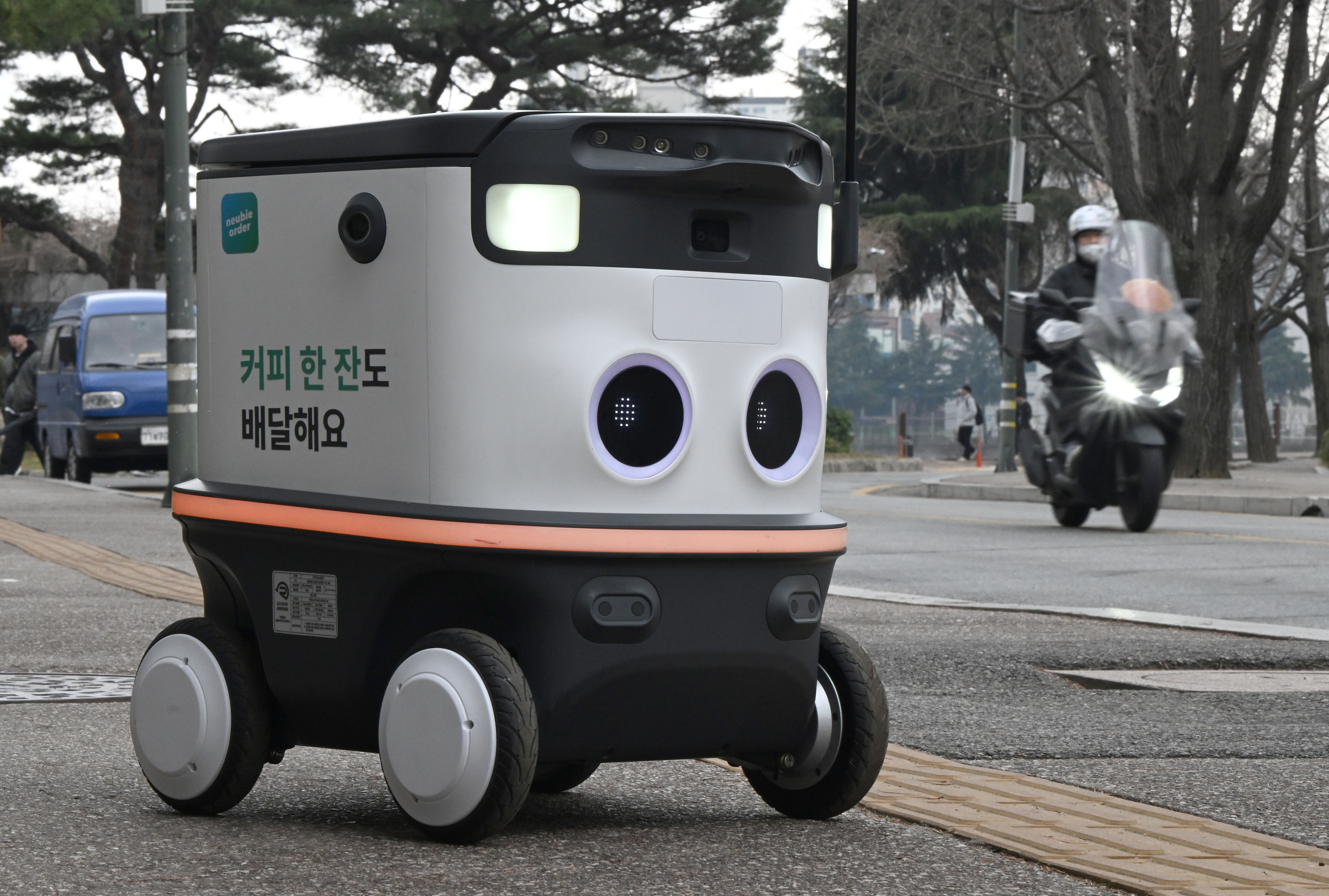 21일 서울 건국대에서 배달로봇 뉴비가 배달하던 중 너머로 배달오토바이의 모습이 보이고 있다. 2024.3.21 박지환기자