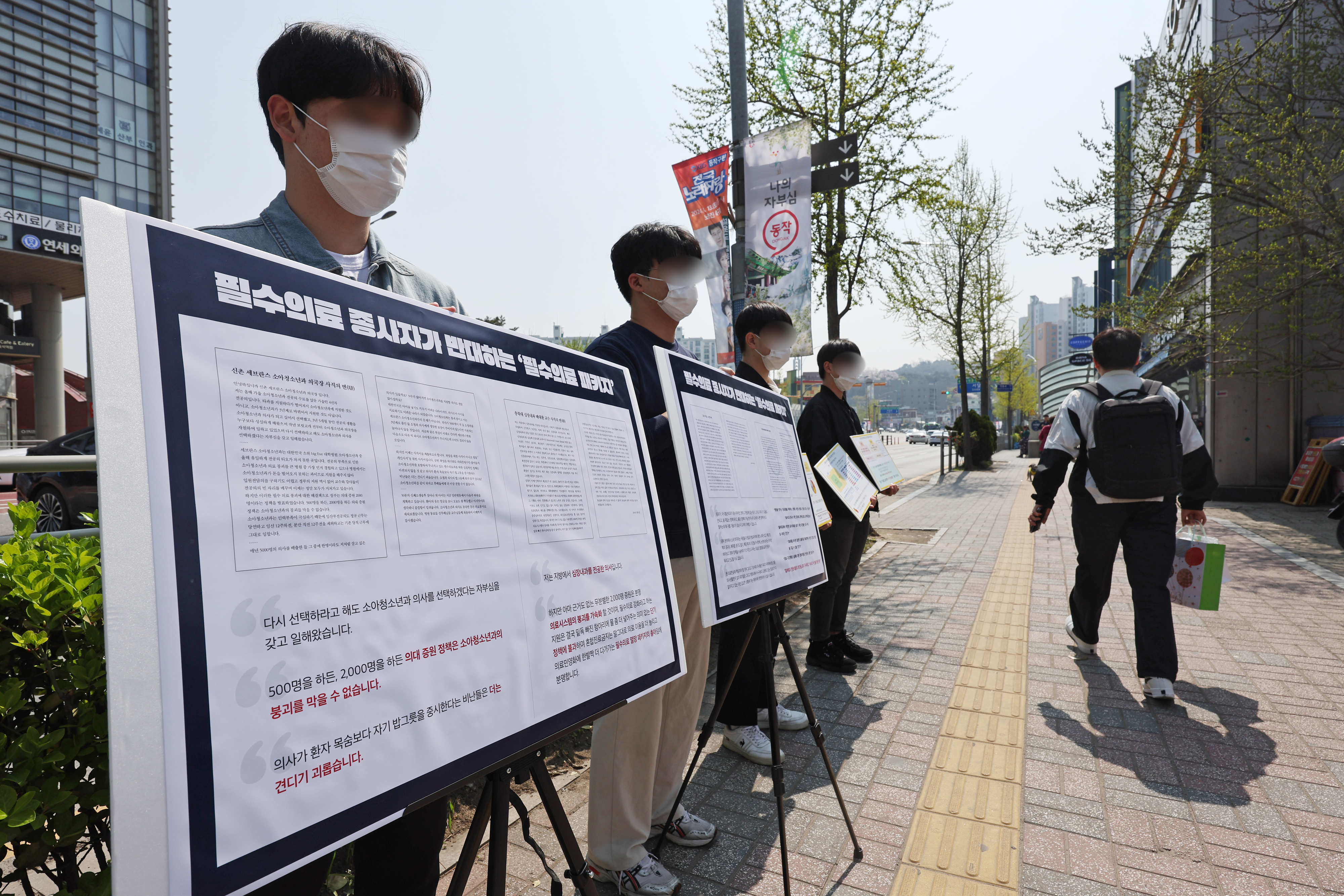 중앙대의대비상시국대응위 관계자들이 서울 동작구 흑석역 인근에서 필수의료 패키지 및 의대 증원을 규탄하는 팻말을 들고 있는 모습. 연합뉴스