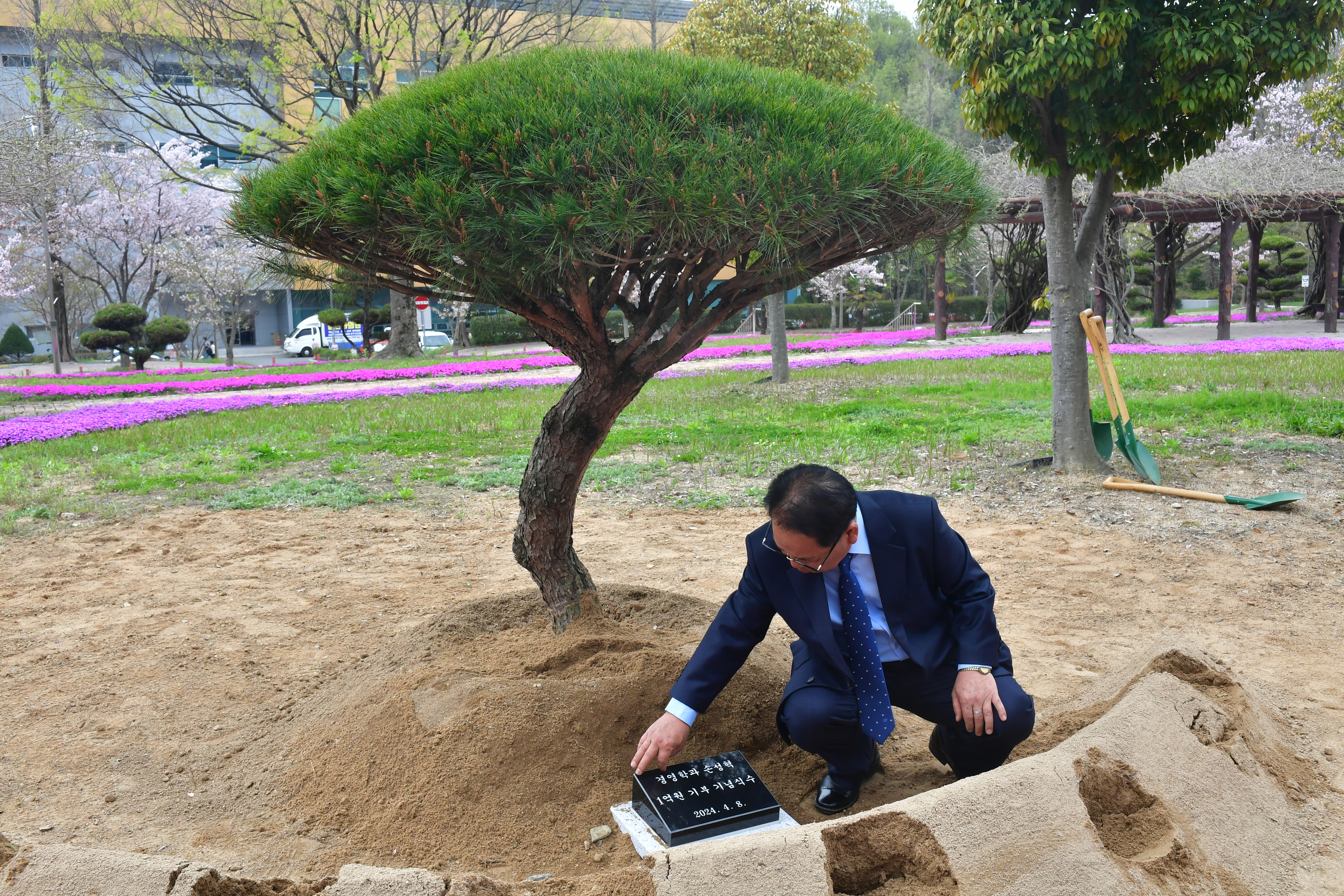 국립창원대학교 경영대학 앞에 심은 기념식수. 고 손성혁씨 아버지인 손명동씨가 비석을 만지고 있다. 2024.4.8. 국립창원대 제공