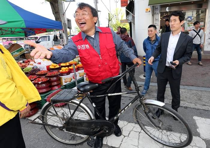 이정현 전 의원이 2016년 4월 14일 전남 순천시 역전시장에서 자전거를 타고 다니며 당선 인사를 하는 모습. 순천 연합뉴스