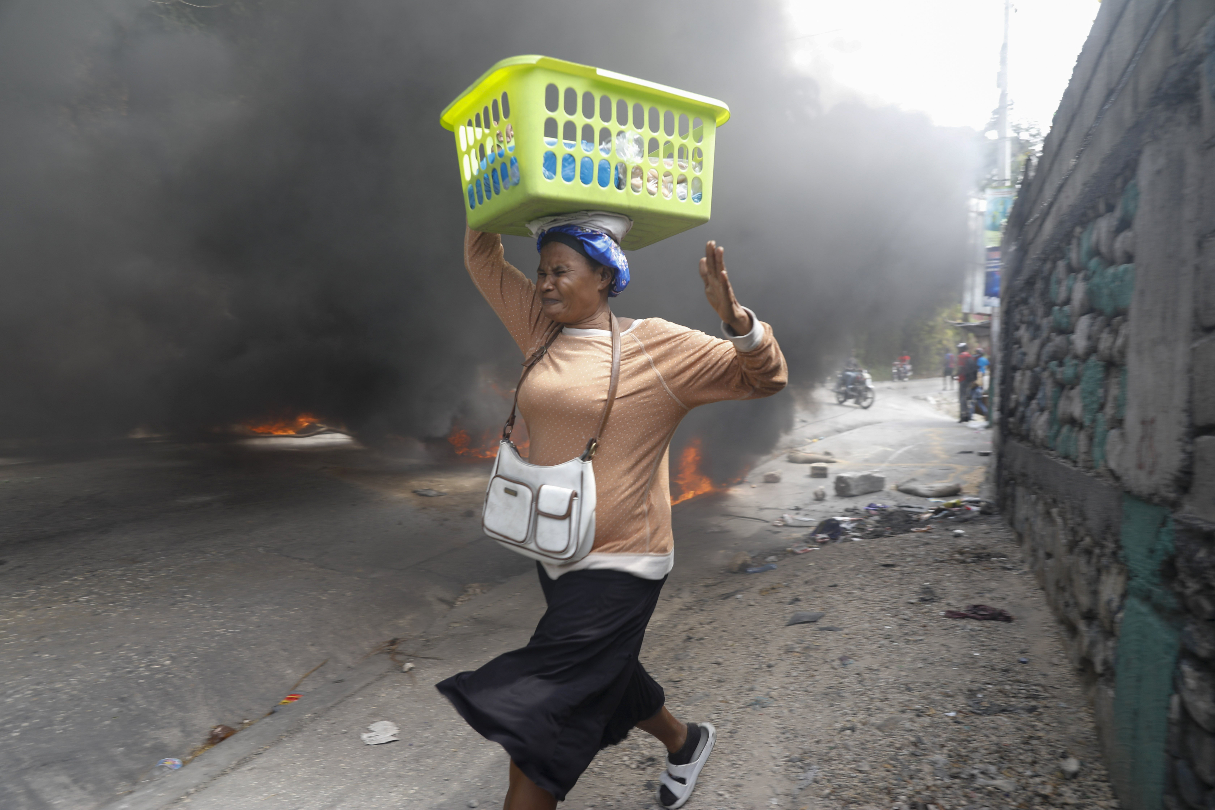 지난 5일(현지시간) 아이티 수도 포르토프랭스에서 한 여인이 불붙은 타이어 옆을 황급히 지나가고 있다. 아리엘 앙리 총리 사임을 요구하는 시위대는 도로를 점거한 채 폐타이어에 불을 지르거나 주요 시설물에 돌을 던지는 등 격렬한 시위를 벌였다. AP 연합뉴스