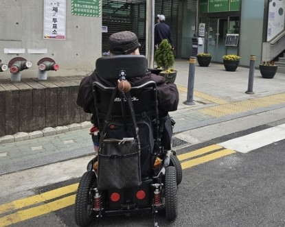 뇌병변 장애인 김명학씨가 투표를 위해 10일 서울 종로구 이화동주민센터에 전동 휠체어를 탄 채 들어가고 있다.