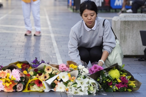 한 여성이 14일 조엘 카우치의 범행으로 6명이 사망한 본다이 정션의 쇼핑몰에 꽃을 헌화하며 피해자들을 애도하고 있다. 시드니 AP 연합뉴스