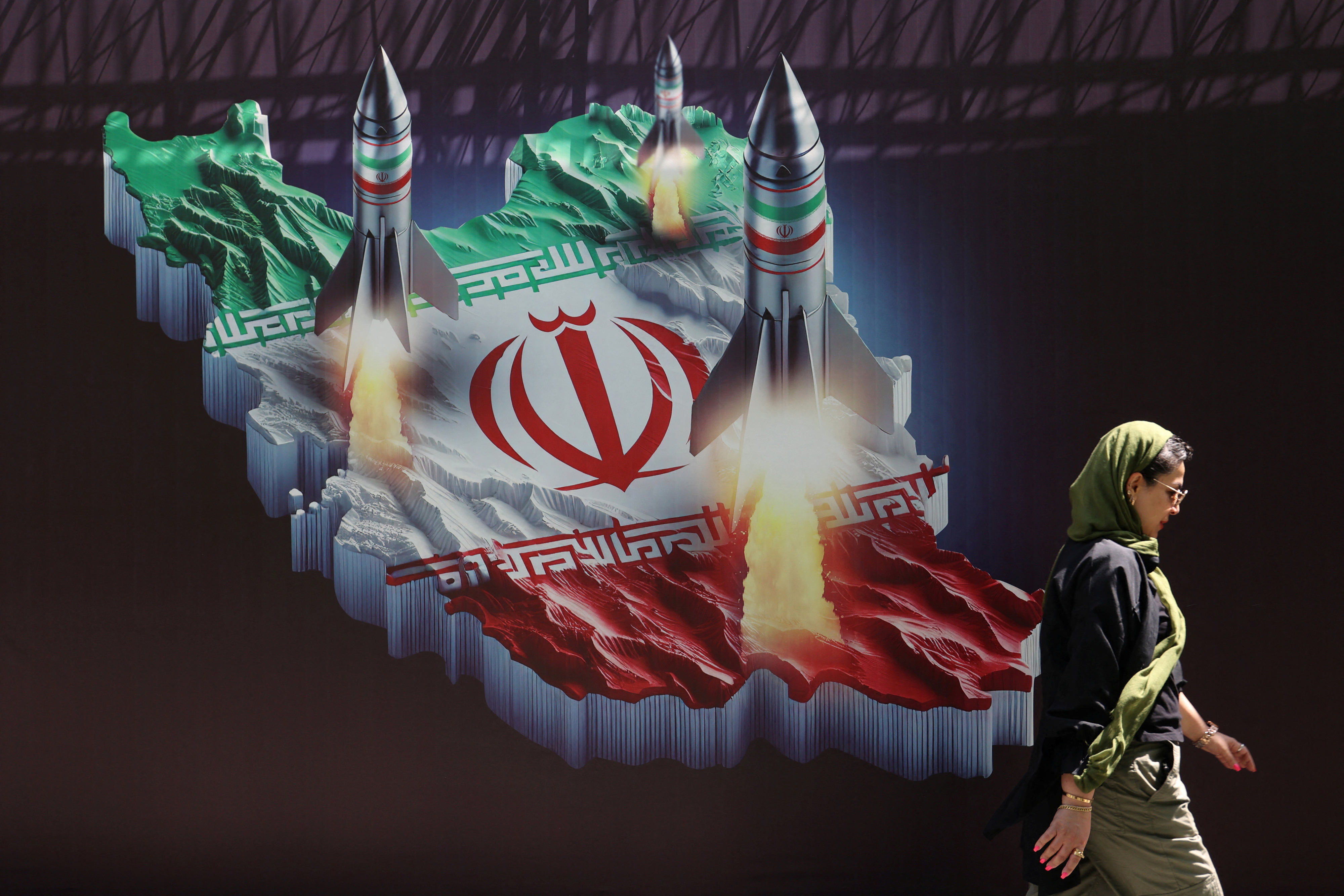 19일(현지시간) 이란 테헤란의 거리에서 한 이란 여성이 이란 미사일 사진이 있는 반이스라엘 현수막 앞을 지나고 있다. 2024.4.19 테헤란 로이터 연합뉴스