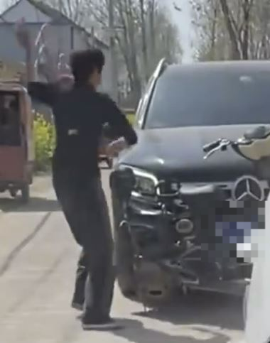 한 중국 여성이 자기 농작물을 밟고 지나간 외제 차를 향해 벽돌을 던지는 모습. 바이두 캡처