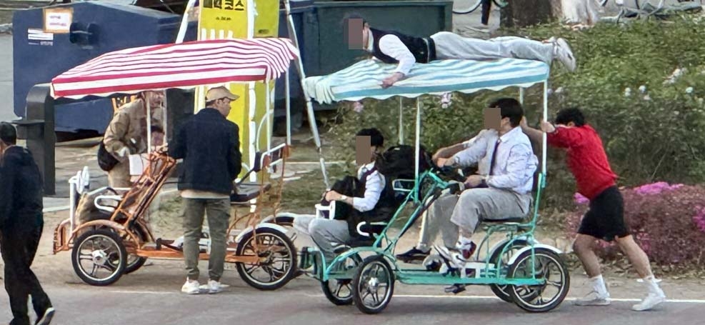 23일 서울 영등포구 여의도 한강공원 자전거 도로에서 사람이 지붕 위에 올라탄 4인승 자전거를 또 다른 사람이 뒤에서 밀고 있다.