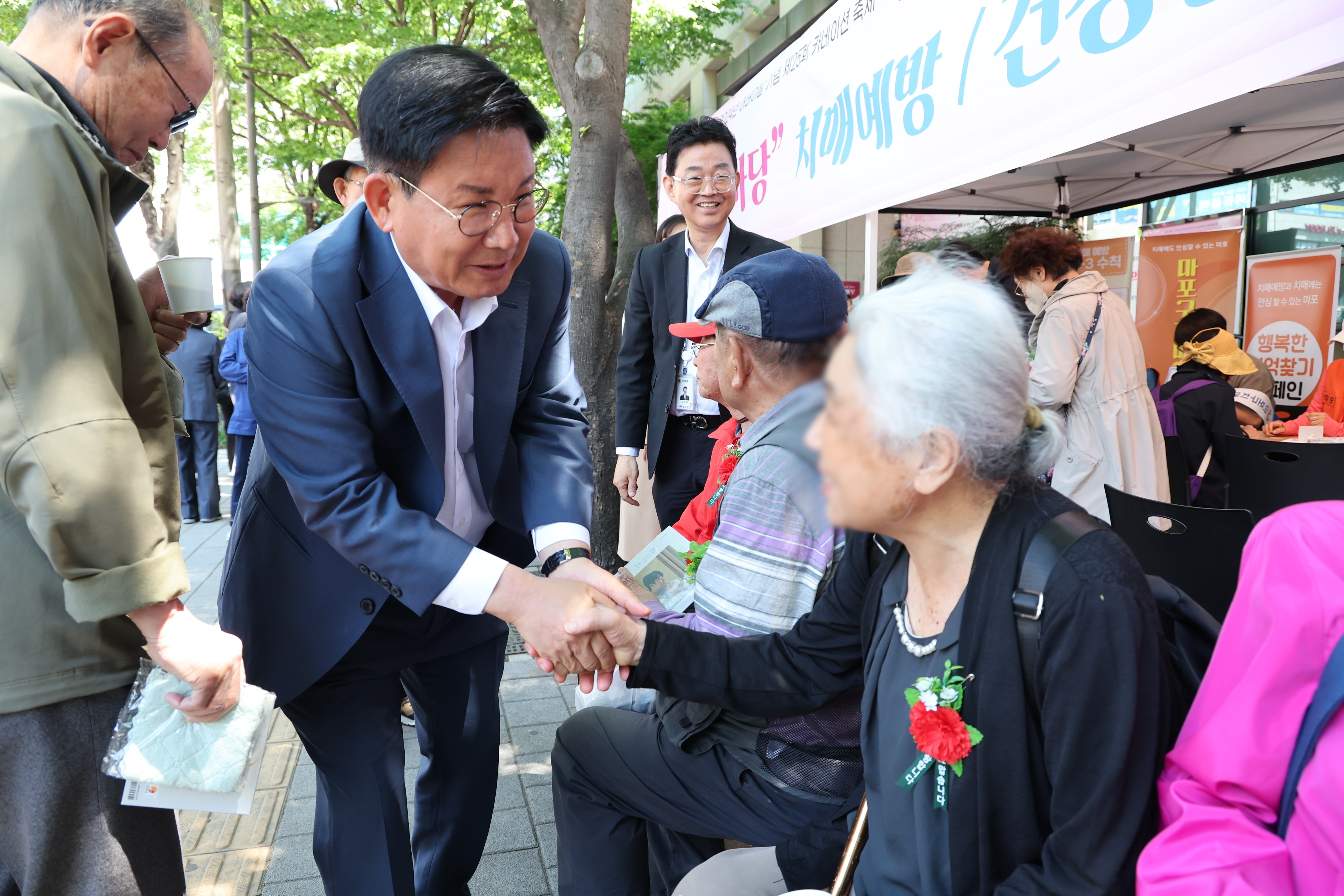 8일 서울 마포구 시립마포노인종합복지관을 찾은 박강수(왼쪽 두번째) 마포구청장이 ‘어르신과의 동행’ 행사에 참석한 노인과 인사를 나누고 있다. 마포구 제공