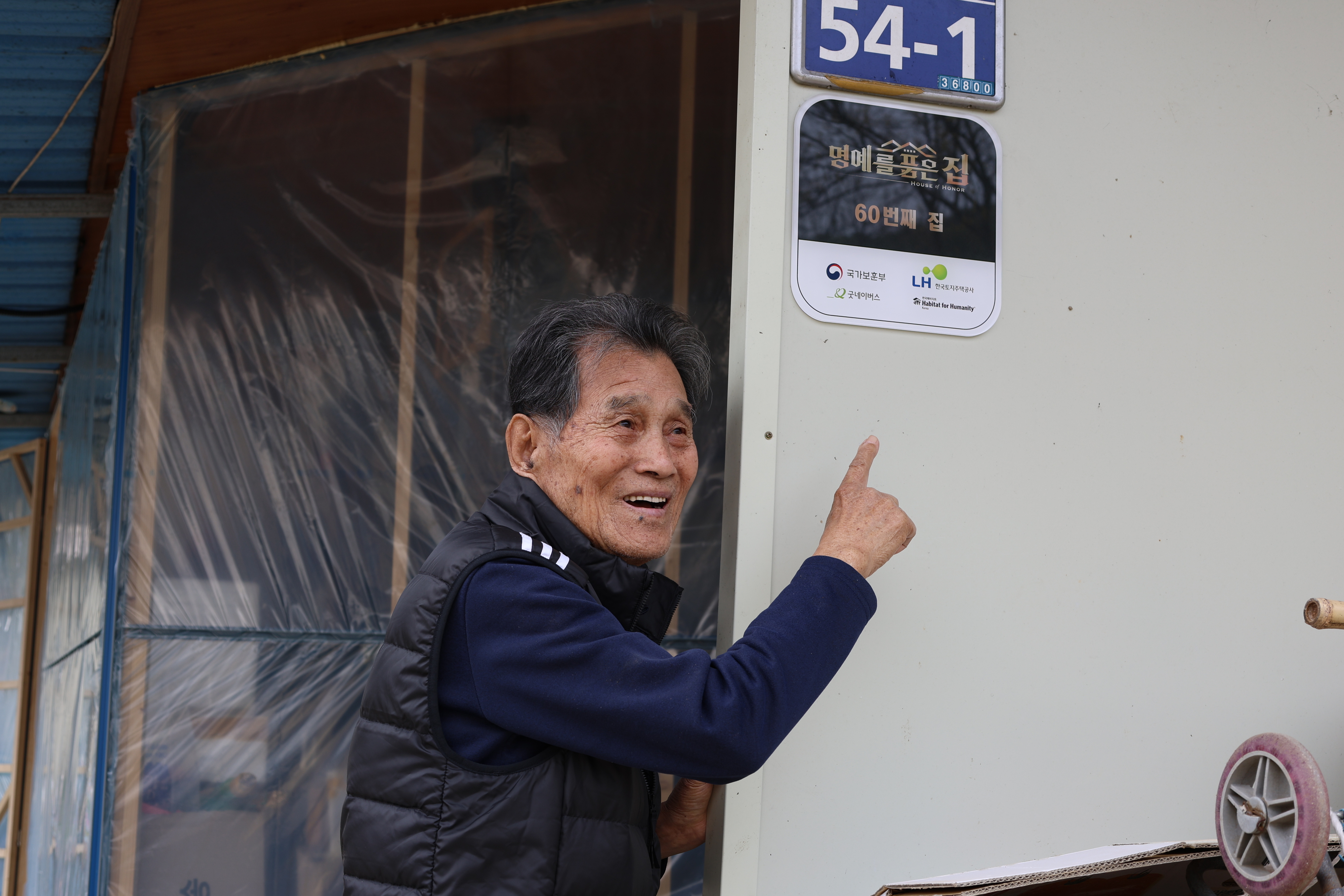 경북 예천군에 사는 국가유공자 김정석(93)씨가 한국토지주택공사(LH)의 보훈 영웅 주거개선 사업인 ‘명예를 품은 집’ 현판을 가리키고 있다. LH 제공