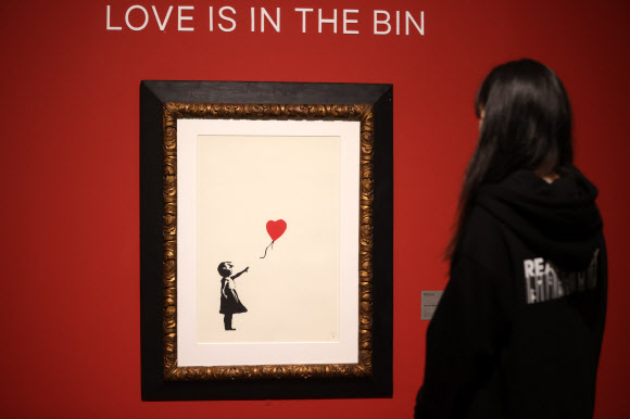 9일 오후 서울 중구 그라운드서울에서 열린 ‘리얼뱅크시’ 프레스데이에서 참석자들이 ‘풍선을 든 소녀’를 둘러보고 있다. 오는 10일 개막하는 전시는 페스트 컨트롤의 공식 인증을 받은 뱅크시 작품 29점을 선보인다. 2024.5.9  연합뉴스