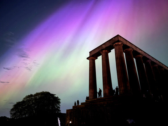 This handout photo taken and released by Jacob Anderson shows the northern lights or aurora borealis during a solar storm over the National Monument of Scotland in Edinburgh on May 10, 2024. The most powerful solar storm in more than two decades struck Earth on May 10, triggering spectacular celestial light shows in skies from Tasmania to Britain -- and threatening possible disruptions to satellites and power grids as it persists into the weekend. AFP 연합뉴스