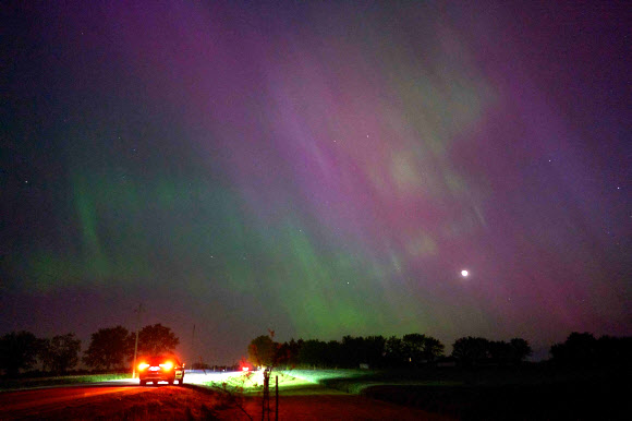 People stop along a country road near London, Ontario to watch the Northern lights or aurora borealis during a geomagnetic storm on May 10, 2024. The most powerful solar storm in more than two decades struck Earth on May10, 2024, triggering spectacular celestial light shows in skies from Tasmania to Britain -- and threatening possible disruptions to satellites and power grids as it persists into the weekend. Auroras are often observed in Canada‘s northern regions, but rarely in southern Ontario. AFP 연합뉴스