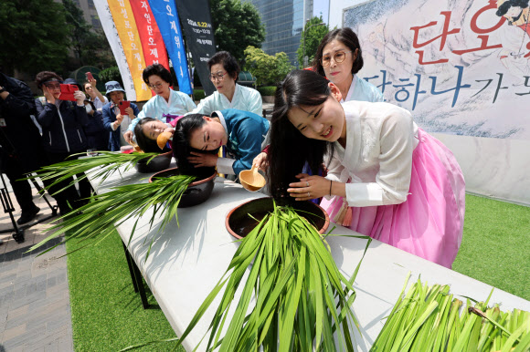 22일 서울 중구 청계광장에서 전국단오제연합 주최로 열린 ‘단오, 단 하나가 되다’ 행사에서 참가자들이 창포머리감기 시연을 보이고 있다. 2024.5.22  연합뉴스