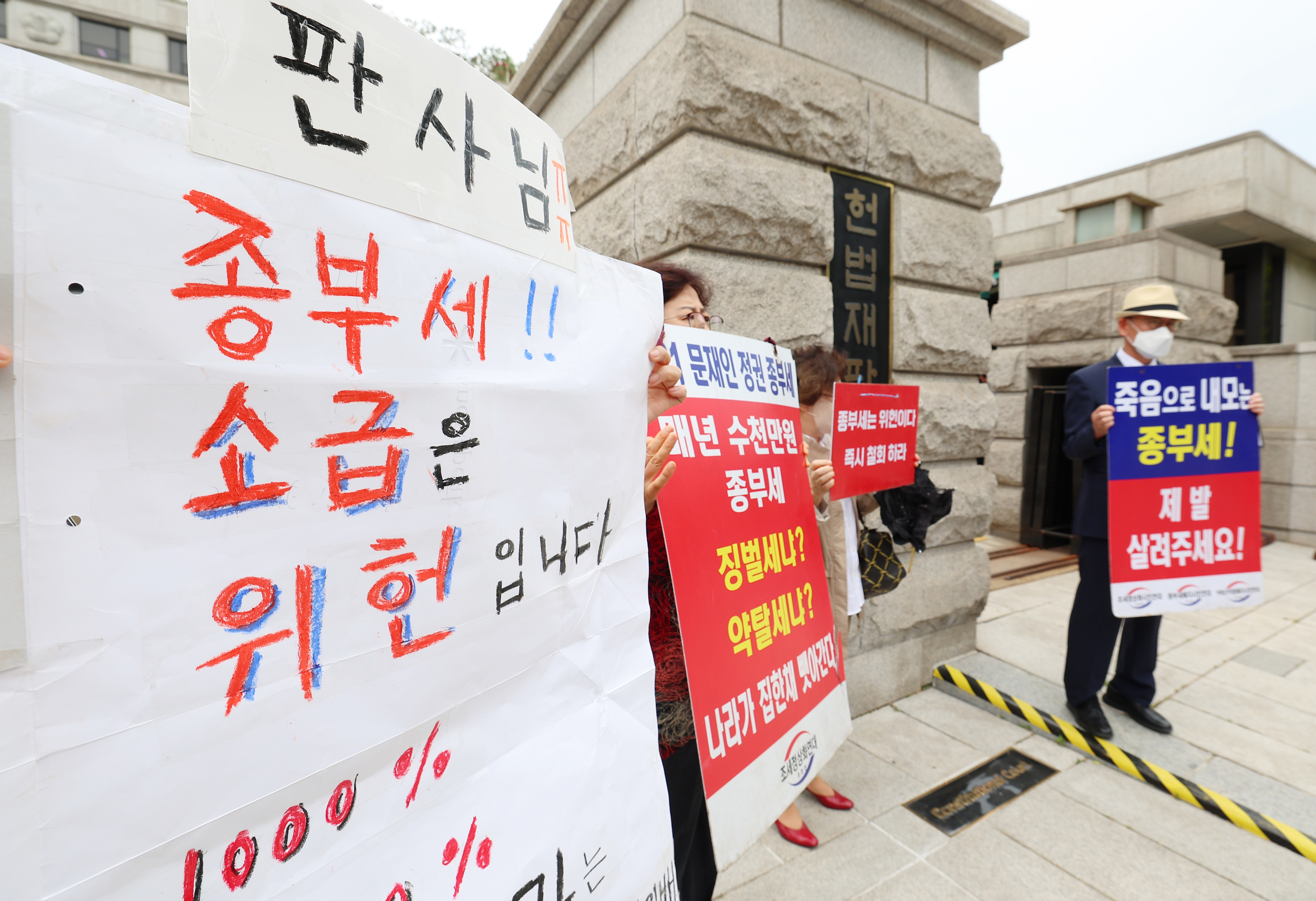 30일 오후 서울 종로구 헌법재판소 앞에서 시민들이 종부세 규탄 피켓을 들고 서 있다. 연합뉴스