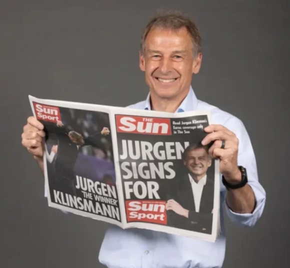 영국 타블로이드지 ‘더 선’의 유로 2024 칼럼니스로 활동하게 된 위르겐 클린스만 전 대표팀 감독이 해당 매체를 펼쳐보이며 웃고 있다. 더 선 홈페이지 캡처