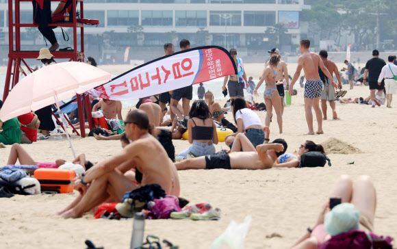 한낮 최고 기온이 29도까지 오르며 한여름 같은 날씨를 보인 11일 오후 부산 해운대구 해운대해수욕장에 피서객들이 태닝을 하며 시간을 보내고 있다. 2024.6.11  연합뉴스
