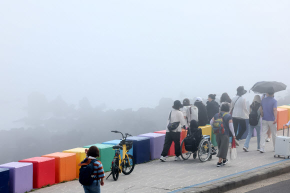 제주도 해안에 바다 안개가 짙게 낀 12일 오전 제주시 도두1동 무지개 해안도로를 찾은 관광객들이 정취를 즐기고 있다. 2024.6.12 연합뉴스