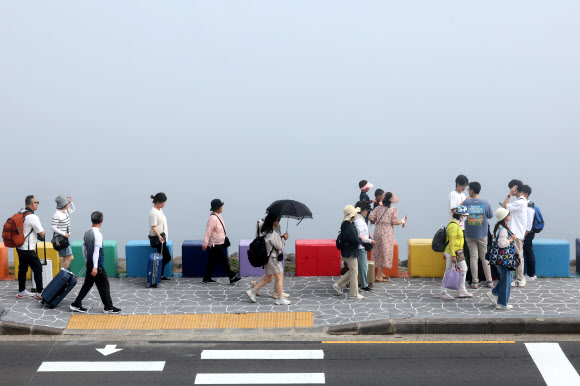 제주도 해안에 바다 안개가 짙게 낀 12일 오전 제주시 도두1동 무지개 해안도로를 찾은 관광객들이 정취를 즐기고 있다. 2024.6.12 연합뉴스