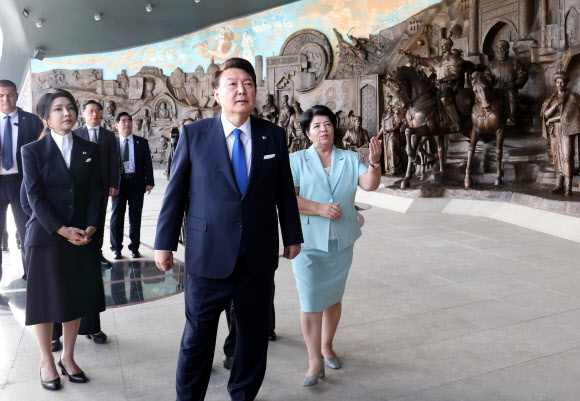 우즈베키스탄을 국빈 방문 중인 윤석열 대통령과 김건희 여사가 13일(현지시간) 타슈켄트 양기 우즈베키스탄 공원광장에 위치한 독립기념비를 방문해 하단 부조에 대한 설명을 듣고 있다.    2024.6.13  연합뉴스