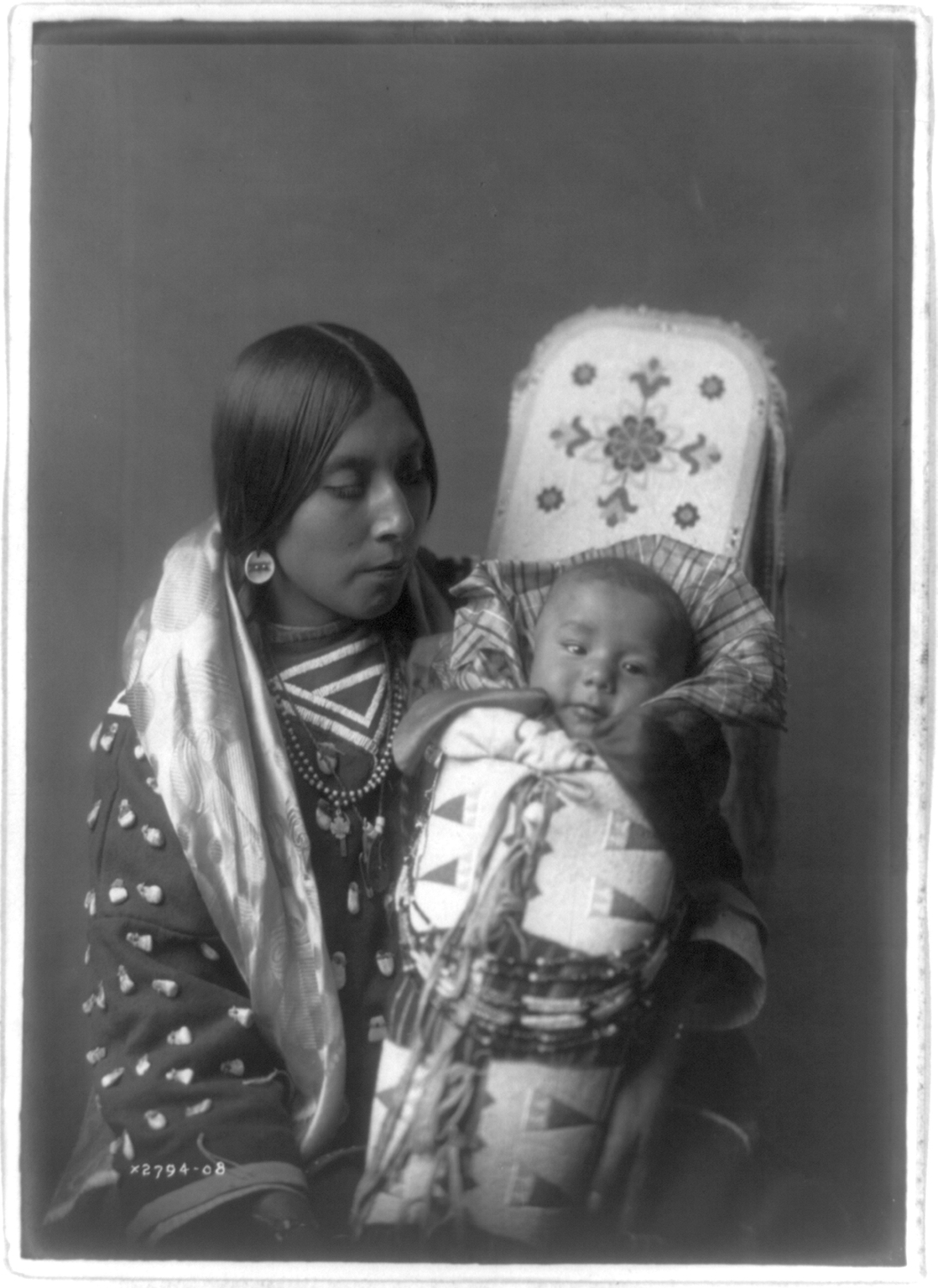 사진작가 에드워드 커티스의 ‘압사로가족 어머니와 아이’(1908년). 온몸을 감싼 채 얼굴만 드러낼 수 있게 만든 아기 요람이 인상적이다.  국립중앙박물관 제공