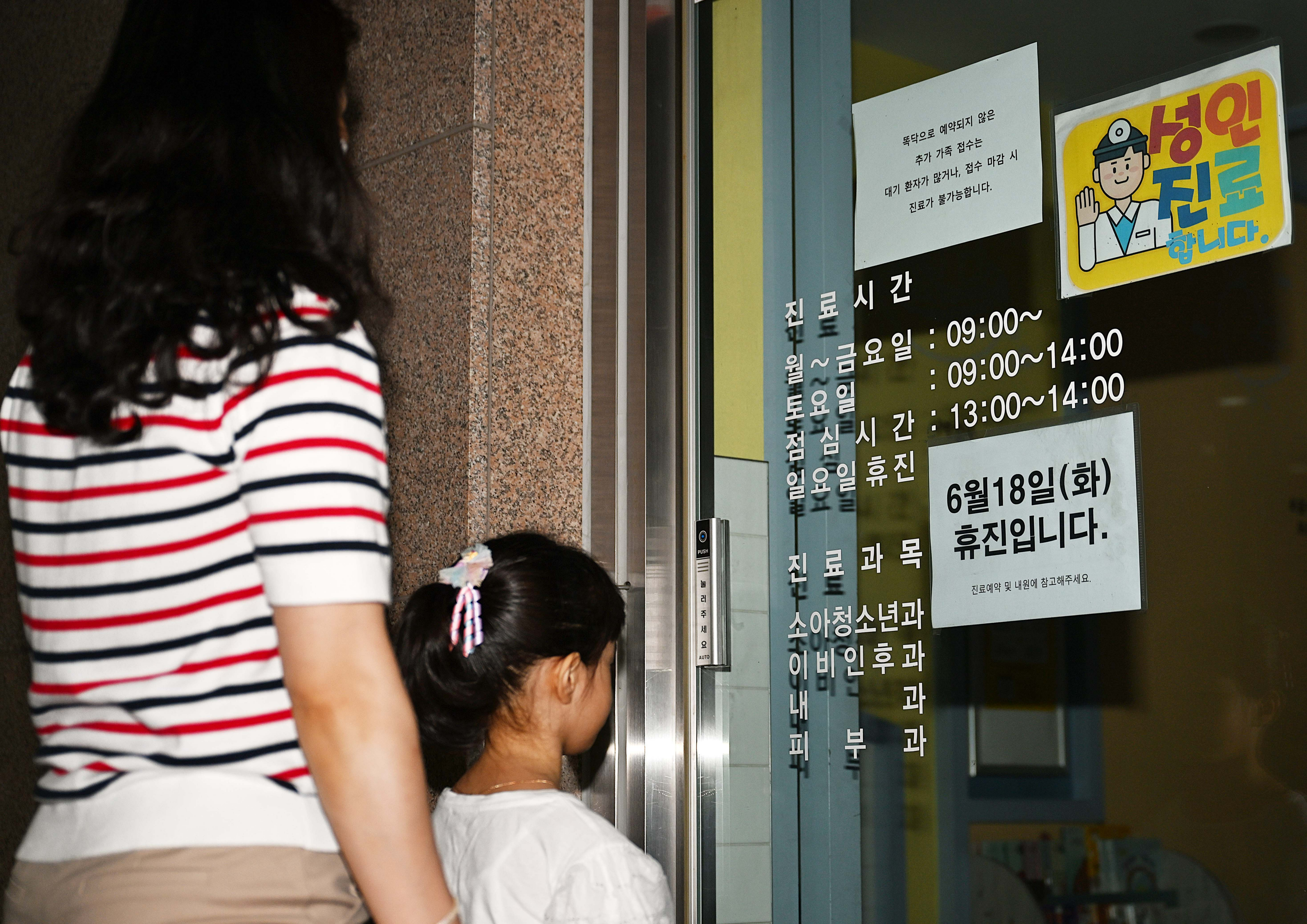 대한의사협회가 집단 휴진에 나선 18일 서울 시내의 한 소아청소년과를 찾은 엄마와 아이가 병원 휴진을 알리는 안내문을 보고 있다.  오장환 기자