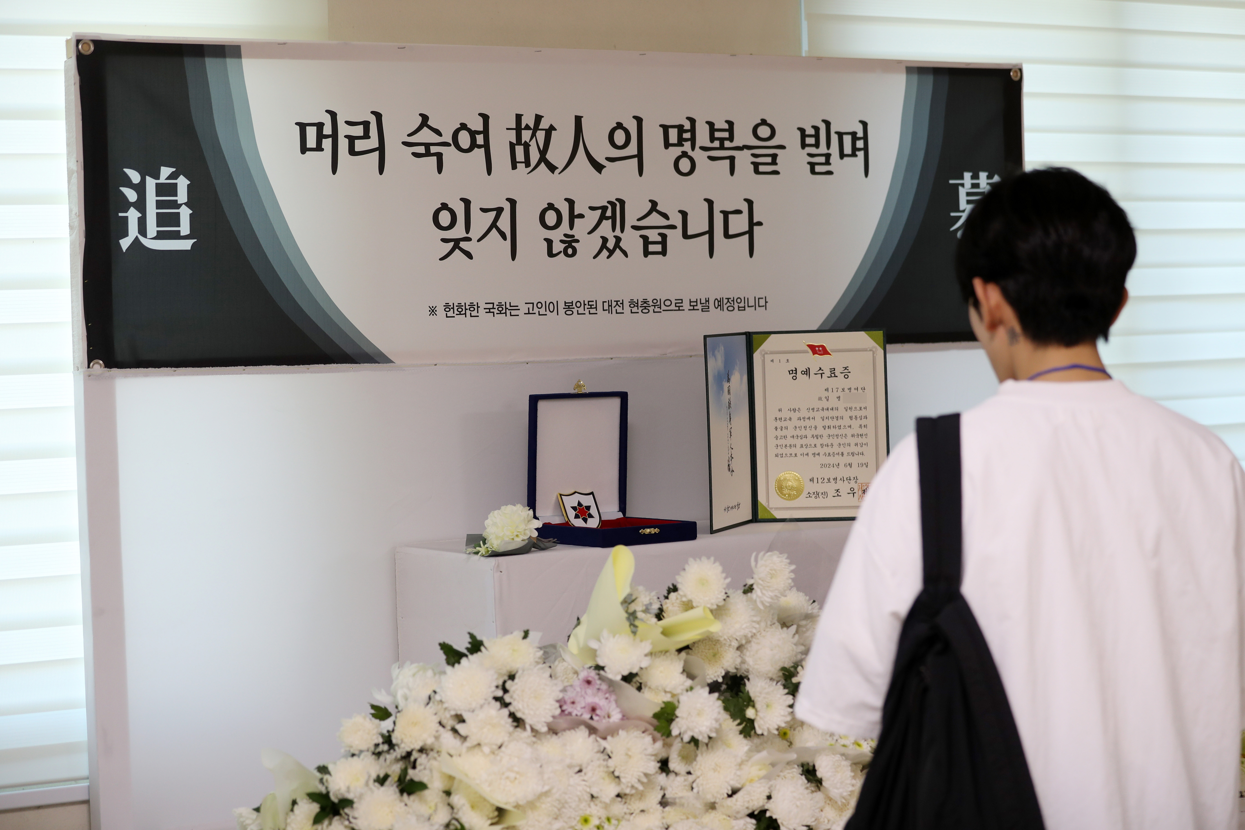 19일 오전 강원 인제군 인제읍 남북리 인제체육관에서 육군 12사단 신병교육대대 수료식이 열렸다. 체육관 입구에 최근 군기훈련(얼차려)을 받다가 쓰러져 숨진 훈련병을 추모하는 공간이 마련돼 한 수료식 참석자가 헌화하고 있다. 2024.6.19 연합뉴스