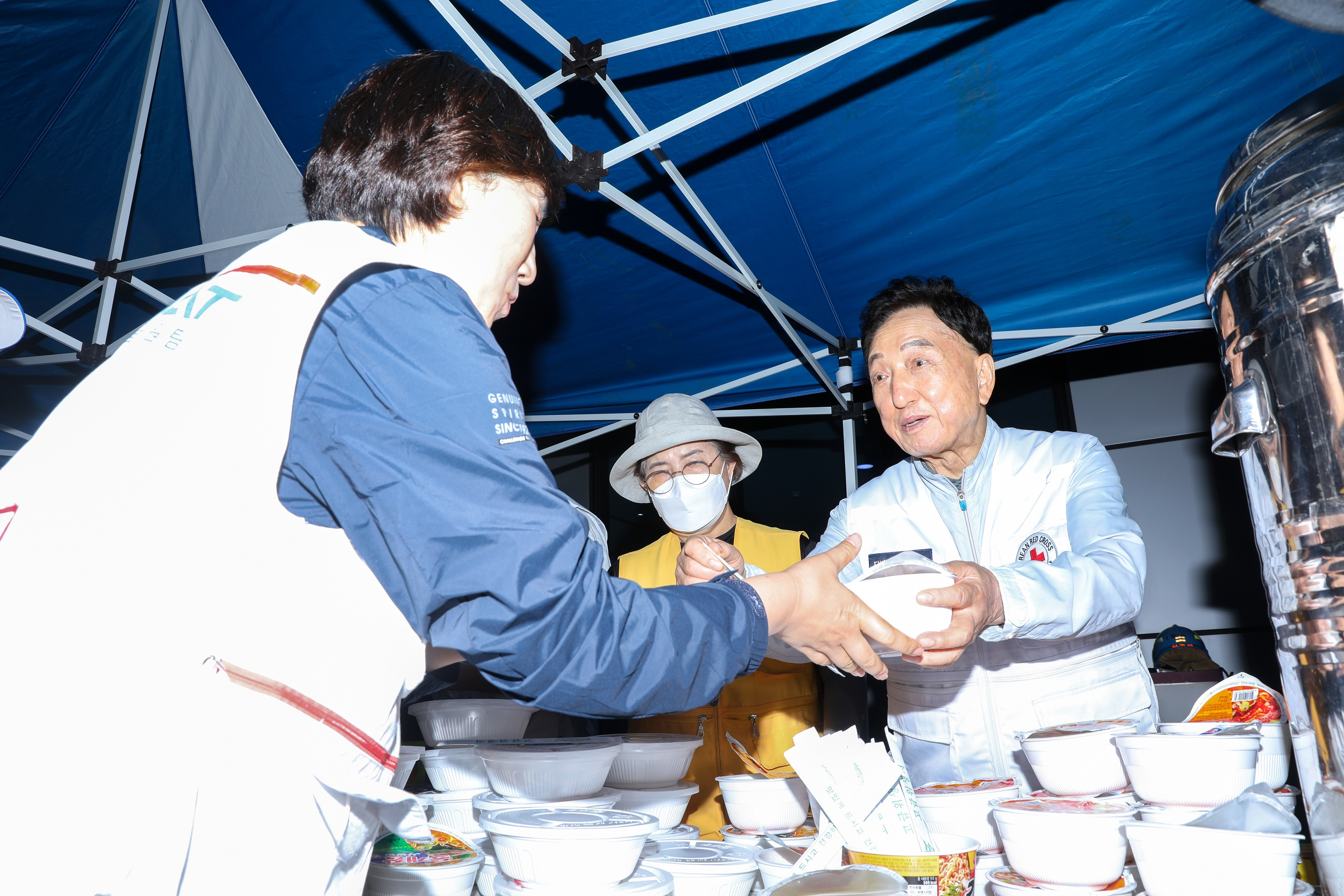 지난 24일 화성 배터리공장 화재 발생 현장을 방문한 김철수(오른쪽) 대한적십자사 회장이 구조대원들에게 석식을 전달하고 있다. 대한적십자사 제공