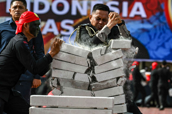 인도네시아 경찰관이 1일(현지시간) 인도네시아 반다에서 열린 인도네시아 경찰 창설 78주년 기념식에서 콘크리트 블록을 깨며 체력을 과시하고 있다. AFP 연합뉴스