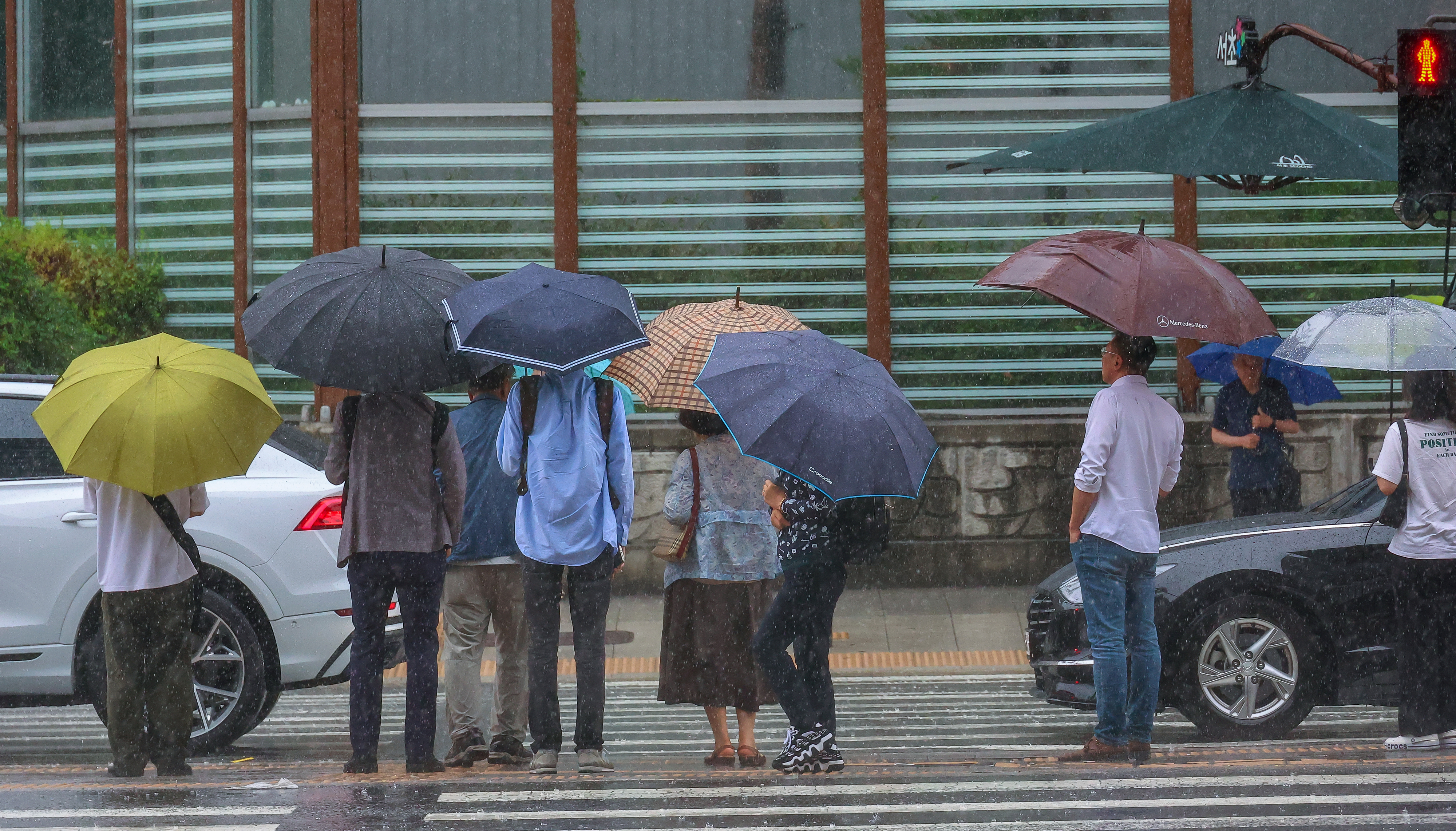 전국적으로 장맛비가 내린 지난 2일 오후 서울 동작구 사당역 인근 버스정류장에서 우산을 쓴 시민들이 횡단보도 신호를 기다리고 있다.  연합뉴스