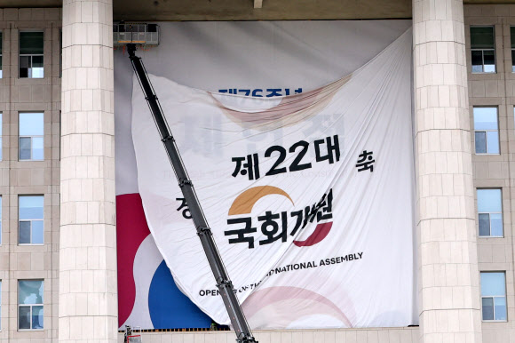 서울 여의도 국회의사당 본관에 설치된 제22대 국회 개원 현수막이 7일 오후 제76주년 제헌절을 알리는 현수막으로 교체되고 있다.  5일 열릴 예정됐던 22대 국회 개원식은 ‘채상병특검법’을 둘러싼 여야 충돌의 여파로 무기한 연기됐다. 2024.7.7  연합뉴스