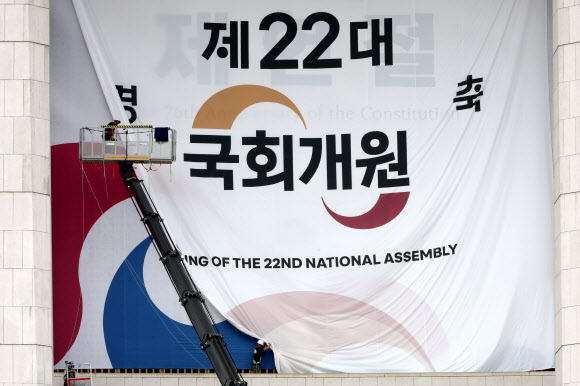 서울 여의도 국회의사당 본관에 설치된 제22대 국회 개원 현수막이 7일 오후 제76주년 제헌절을 알리는 현수막으로 교체되고 있다.  5일 열릴 예정됐던 22대 국회 개원식은 ‘채상병특검법’을 둘러싼 여야 충돌의 여파로 무기한 연기됐다. 2024.7.7  연합뉴스