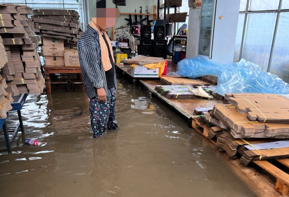 11일 충북 옥천군 군서면 상지리 지경수 마을의 한 주민이 물에 잠긴 농사창고를 바라보고 있다. 2024.7.11  연합뉴스