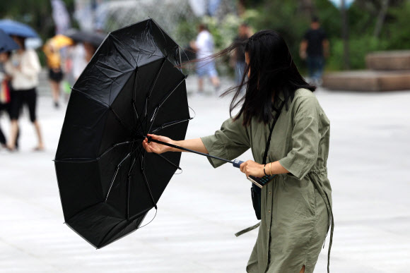 16일 오후 서울 광화문광장에 갑자기 비가 내린 가운데 한 시민의 우산이 뒤집혀 있다. 2024.7.16. 연합뉴스