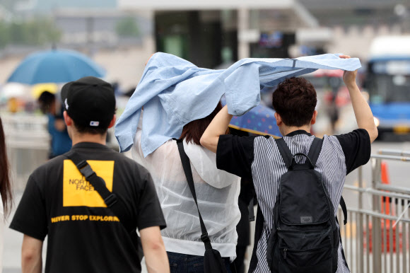 16일 오후 서울 광화문광장에 갑자기 비가 내린 가운데 외국인 관광객들이 겉옷으로 비를 막고 있다. 2024.7.16. 연합뉴스