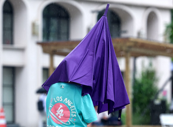 장맛비가 내린 16일 오후 서울 종로구 광화문 광장에서 한 어린이가 우산 속으로 머리를 넣고 있다. 2024.7.16. 연합뉴스