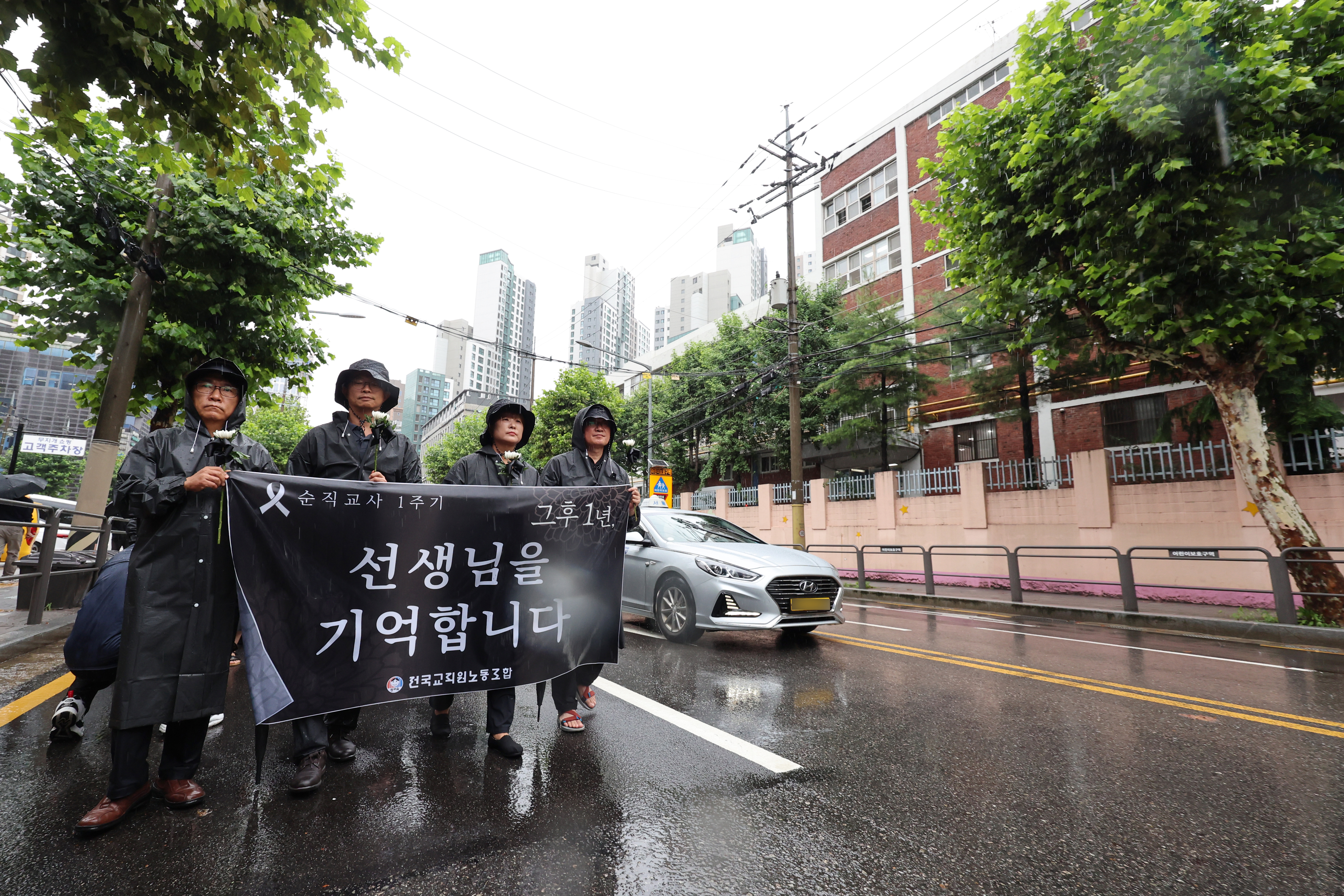 서울 서초구 서이초등학교 교사 순직 1주기인 18일 서이초 사거리에서 전국교직원노동조합 관계자 등 교사들과 교사유가족협의회 관계자가 고인을 추모하는 흰 국화꽃을 든 채 행진하고 있다. 이날 서울, 대전 등 전국 곳곳에서 서이초 교사의 희생을 기리며 추가적인 교육활동 보호 대책을 촉구하는 추모 행사가 열렸다. 연합뉴스