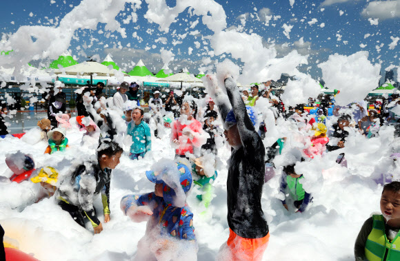 부산 전 지역에 폭염경보가 발효된 29일 부산 남구 용호별빛공원에서 열린 ‘유엔 남구 물놀이 축제’를 찾은 어린이들이 버블체험존에서 친환경 거품 샤워를 하고 있다. 다음 달 9일까지 열리는 이번 물놀이 축제는 타투스티커 체험, 버블체험, 랜덤댄스대결, 에어바운스 풀장, 워터터널, 대형물바가지, 페덜보트 등 5종의 21개 프로그램을 즐길 수 있다. 2024.7.29  연합뉴스