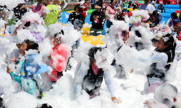 부산 전 지역에 폭염경보가 발효된 29일 부산 남구 용호별빛공원에서 열린 ‘유엔 남구 물놀이 축제’를 찾은 어린이들이 버블체험존에서 친환경 거품 샤워를 하고 있다. 다음 달 9일까지 열리는 이번 물놀이 축제는 타투스티커 체험, 버블체험, 랜덤댄스대결, 에어바운스 풀장, 워터터널, 대형물바가지, 페덜보트 등 5종의 21개 프로그램을 즐길 수 있다. 2024.7.29  연합뉴스