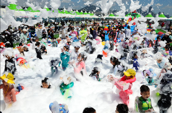 부산 전 지역에 폭염경보가 발효된 29일 부산 남구 용호별빛공원에서 열린 ‘유엔 남구 물놀이 축제’를 찾은 어린이들이 버블체험존에서 친환경 거품 샤워를 하고 있다. 다음 달 9일까지 열리는 이번 물놀이 축제는 타투스티커 체험, 버블체험, 랜덤댄스대결, 에어바운스 풀장, 워터터널, 대형물바가지, 페덜보트 등 5종의 21개 프로그램을 즐길 수 있다. 2024.7.29  연합뉴스