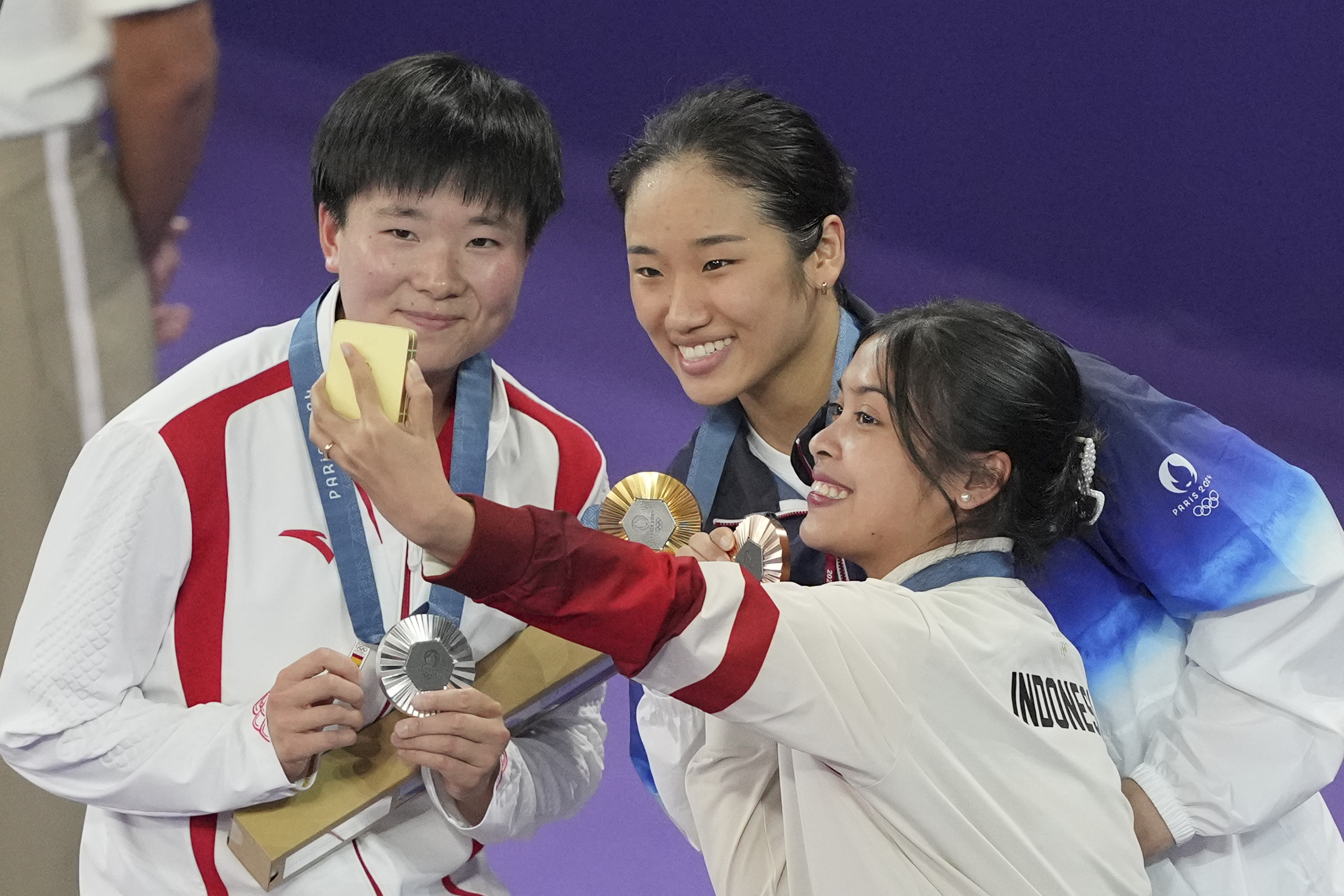 5일(현지시간) 프랑스 파리 포르트드라샤펠 경기장에서 열린 2024 파리 올림픽 배드민턴 여자 단식 시상식에서 금메달을 딴 우리나라의 안세영(가운데)과 은메달리스트 허빙자오(왼쪽·중국), 동메달리스트 그레고리아 마리스카 툰중(인도네시아)이 기념 촬영을 하고 있다. 허빙자오의 오른손에 작은 배지가 들려있다. AP 연합뉴스